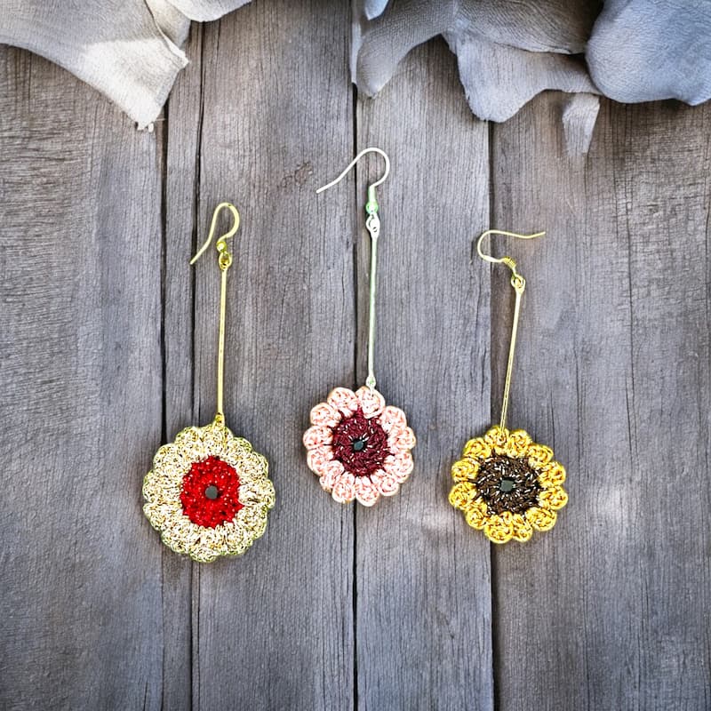 Pendientes largos de crochet con diseño de girasol, hechos a mano con hilo metalizado en tonos rosas y dorado.