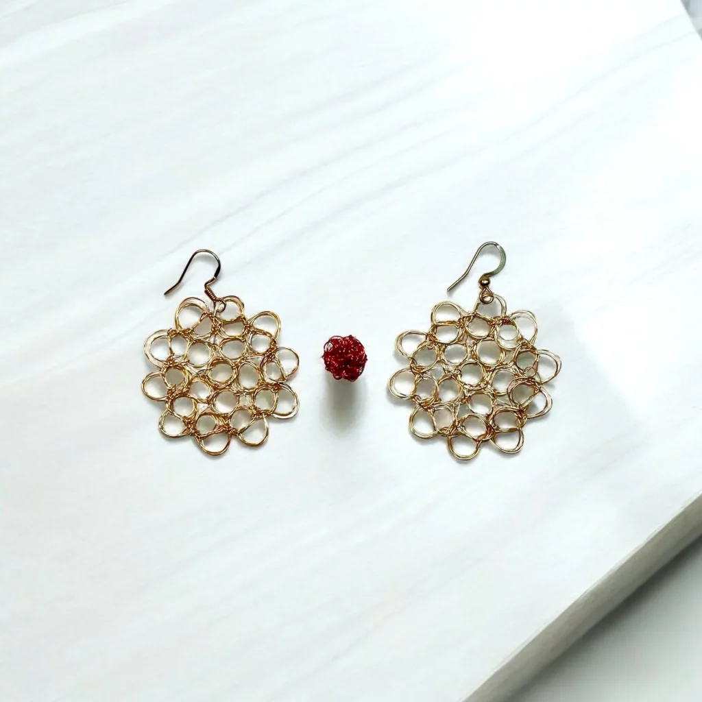 Aretes circulares de alambre dorado tejido en ganchillo con diseño irregular.