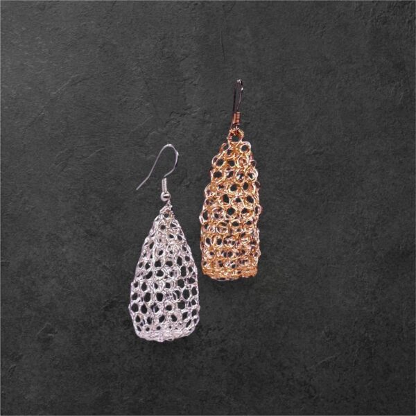 Pendientes Noe en plateado y dorado sobre encimera negra.