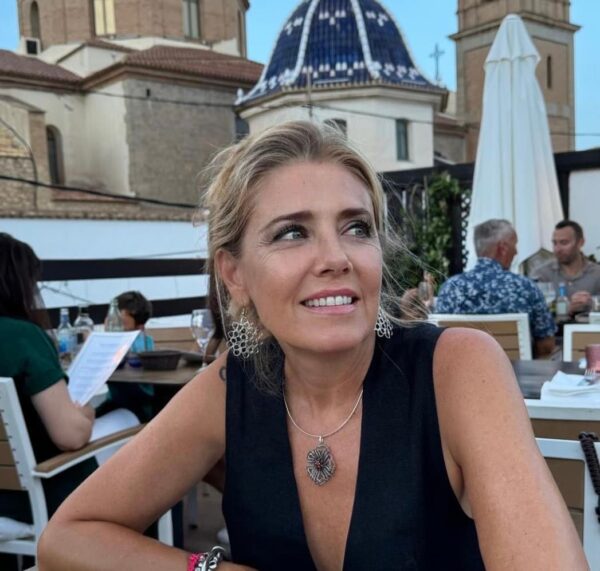 Pendientes de alambre tejido en crochet "Sara" usados por mujer en un evento al aire libre, con fondo arquitectónico y estilo refinado.