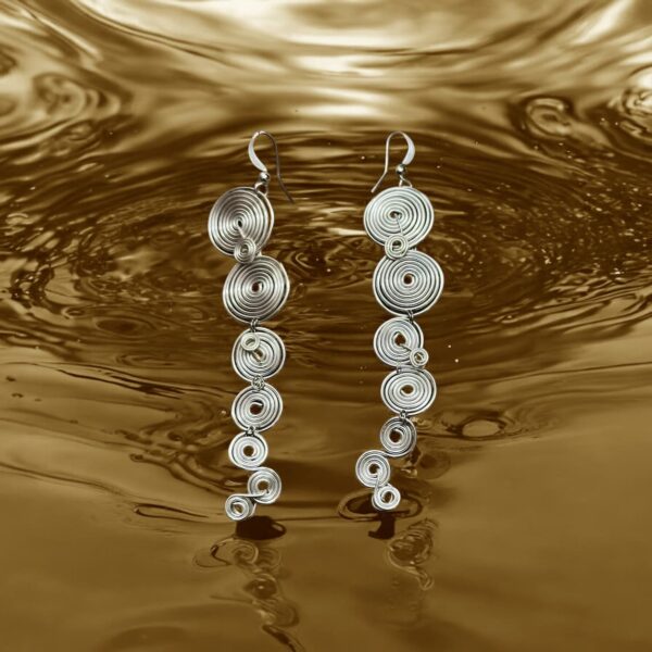 Pendientes largos You de alambre plateado, con diseño en espirales, presentados sobre fondo dorado liquido.