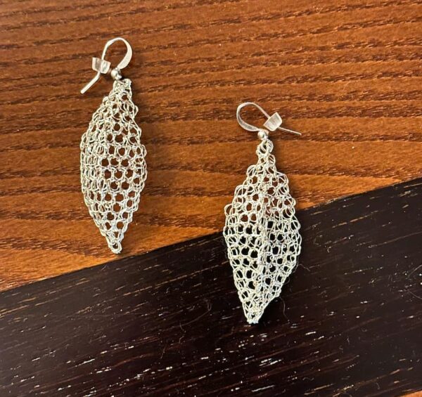 Aretes Gabriela tejido en alambre en punto peruano en forma de rombo sobre una superficie de madera destacando su glamour.